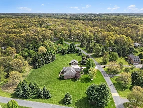 Aerial view of a country home surrounded by lawn and woodland