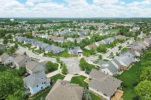 Aerial view of a residential subdivision with lawns, sidewalks, and curving streets