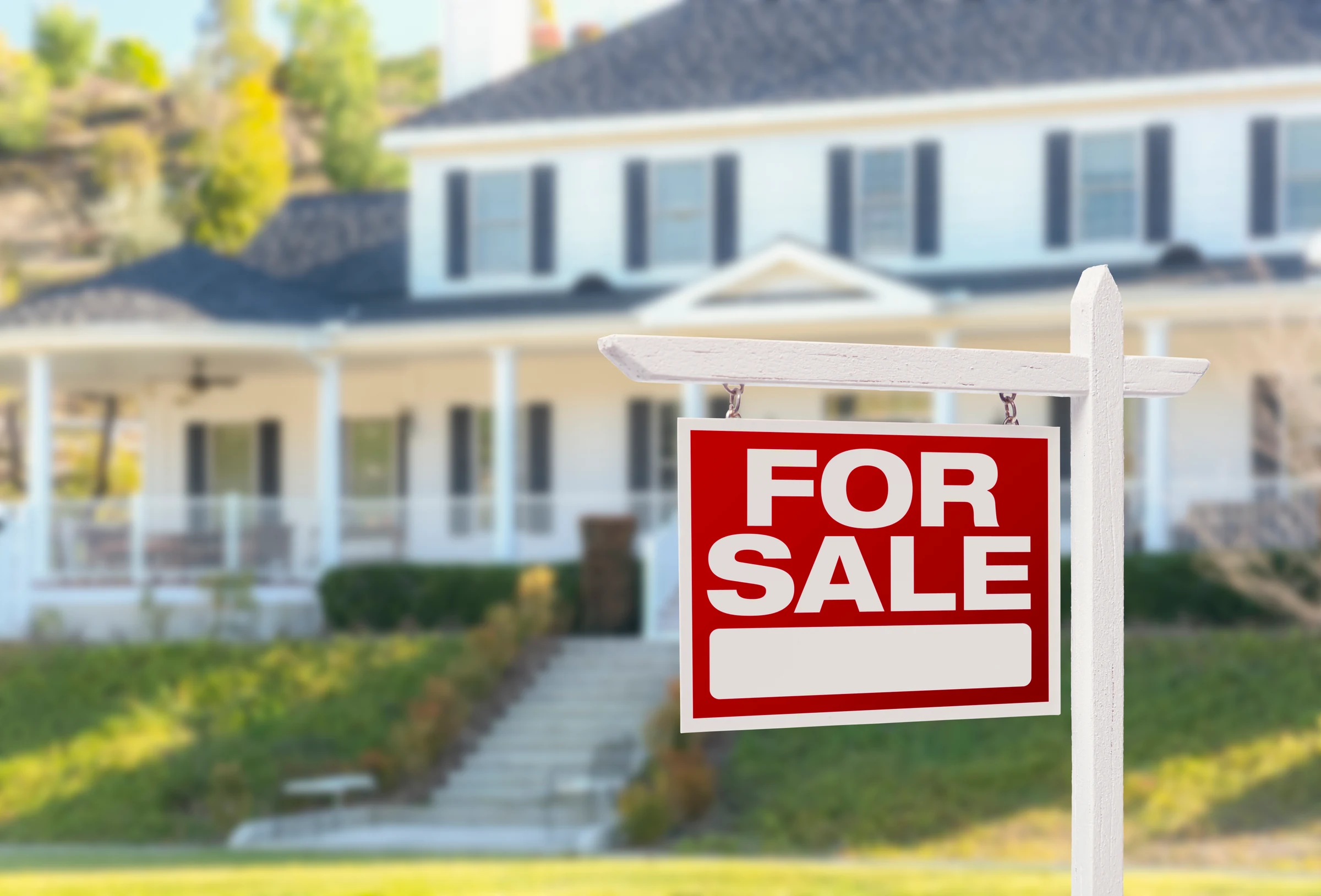 For sale sign on a lawn in front of a home