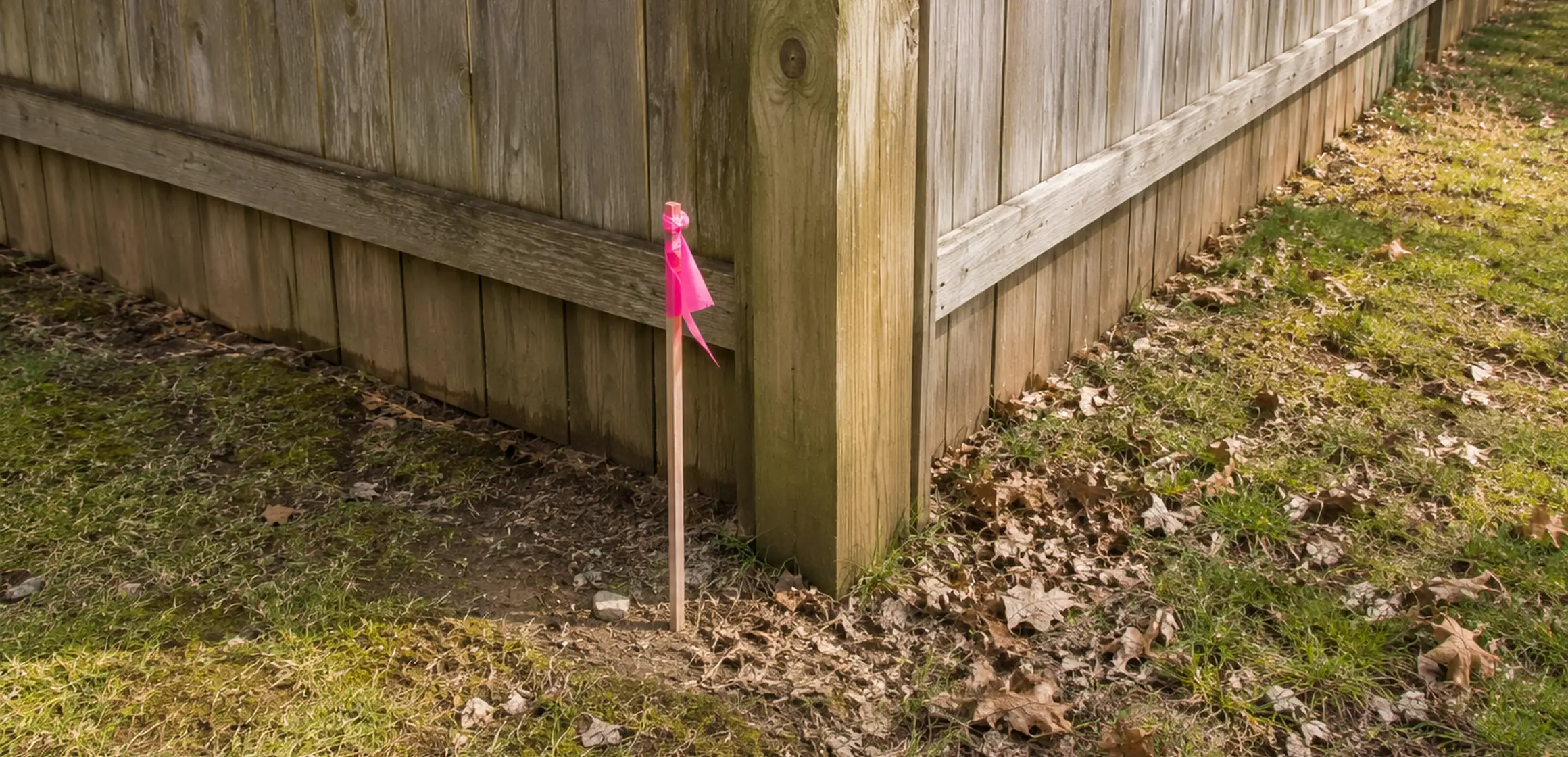 Wooden survey stake and boundary marker at a residential lot corner