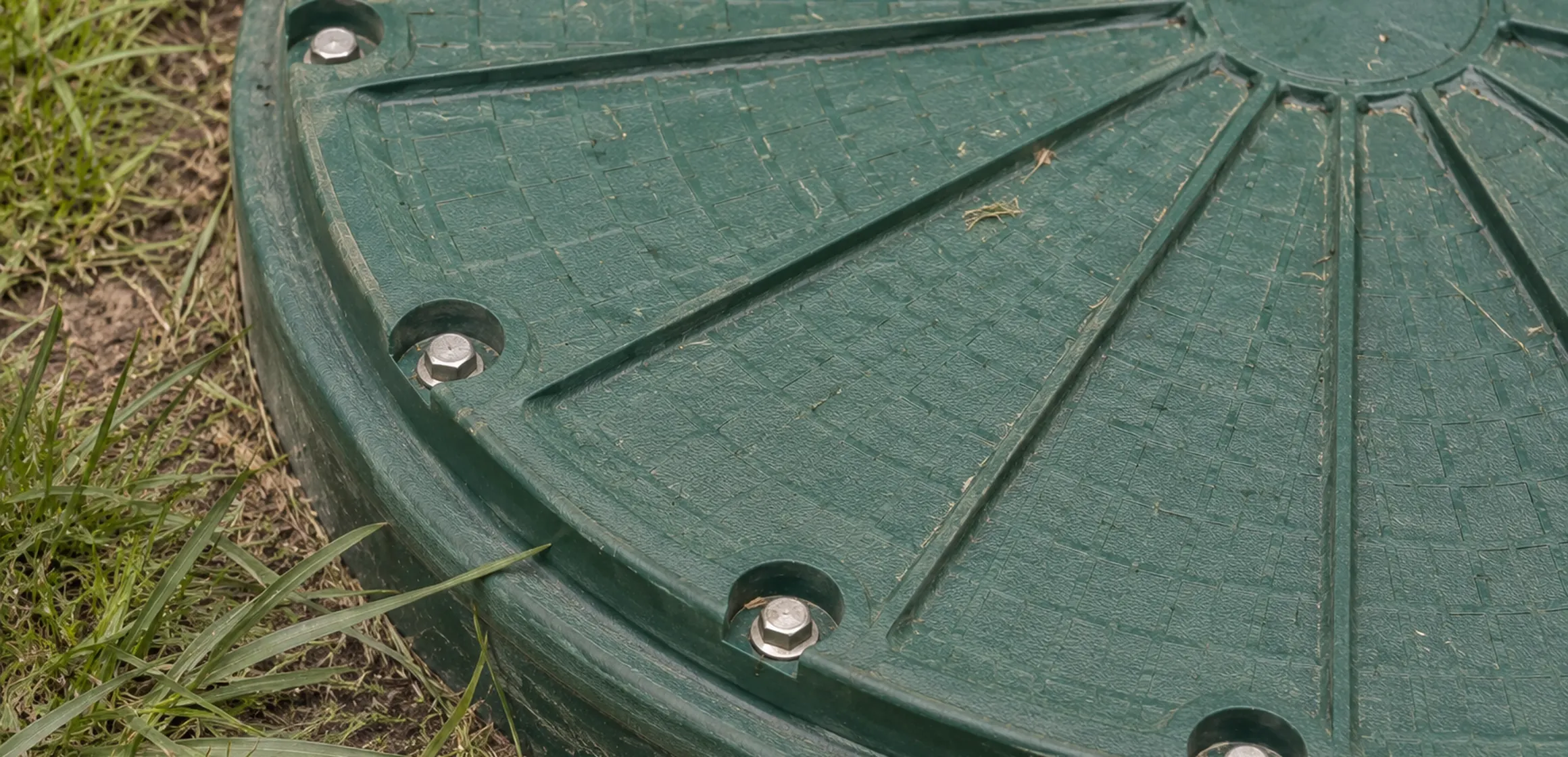 House with septic tank access cover visible in a grassy side yard