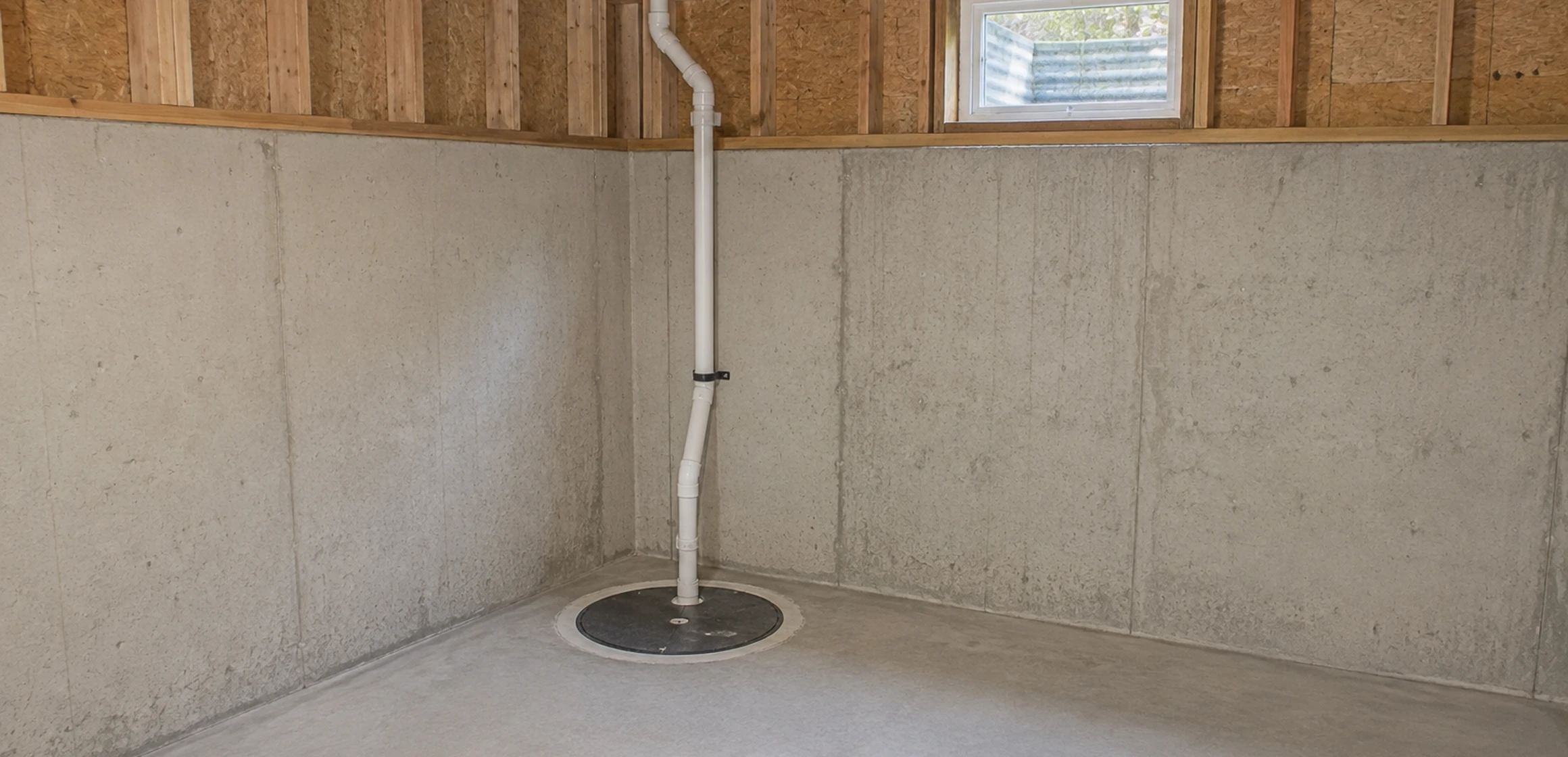 Sump pump basin and discharge pipe in a poured-concrete basement